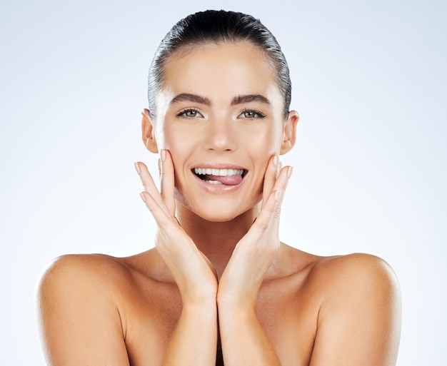 Visage de beauté et portrait de soins de la peau d'une femme en studio avec une peau éclatante naturelle et des dents blanches Modèle esthétique personne mordant la langue pour la dermatologie faciale et le bien-être du spa sur fond clair