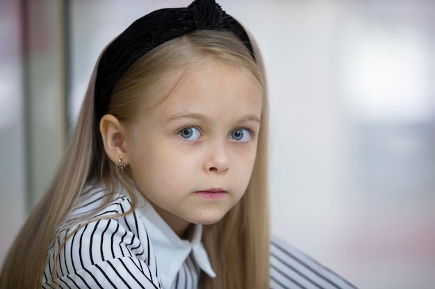 Le visage d'une belle petite fille blonde aux yeux bleus Un enfant d'âge élémentaire