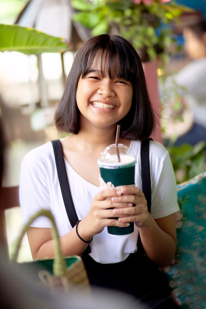 Visage de bonheur adolescent asiatique avec une bouteille de boisson fraîche à la main