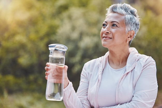 Visage d'une bouteille d'eau et d'une femme âgée dans la nature en pause après un exercice ou un entraînement sportif