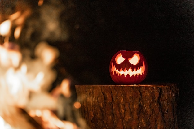 Visage de citrouille d'Halloween avec des bougies allumées et feu de camp en arrière-plan Visage effrayant et feu d'étang