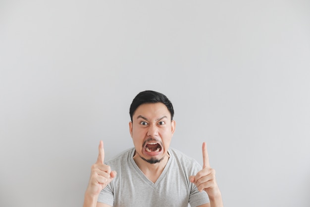 Visage en colère de l&#39;homme en t-shirt gris avec la main pointent sur un espace vide.