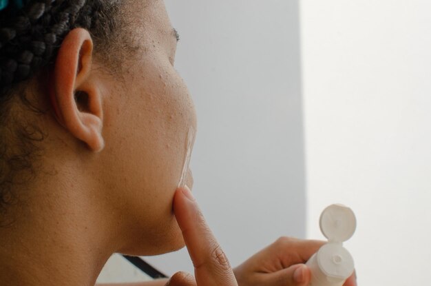 Photo visage comme une toile, mains habiles appliquant une crème pour le visage, créant une routine de soins essentiels pour une peau saine et lumineuse