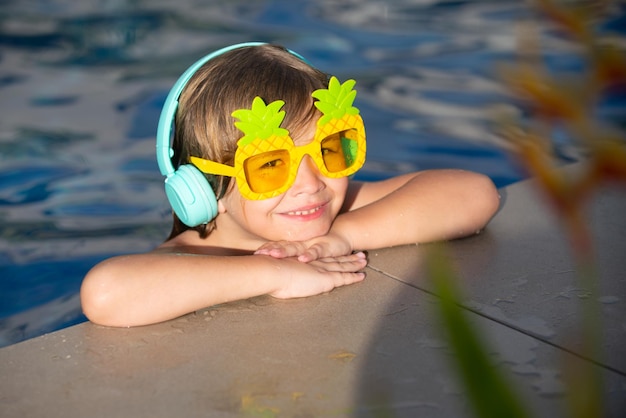 Visage drôle de petit garçon dans des lunettes de soleil drôles dans la piscine en journée ensoleillée vacances d'été pour enfants