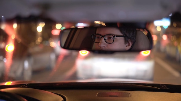 Le visage du conducteur se reflète dans une photo de nuit du rétroviseur