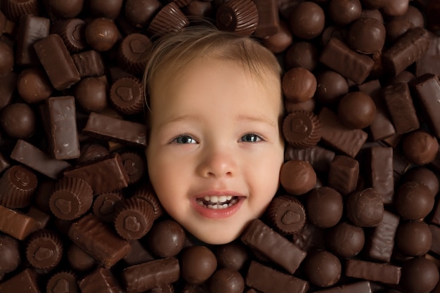 Visage de l'enfant gros plan sur un fond de bonbons au chocolat