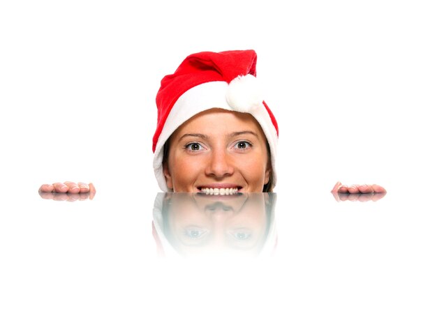 un visage féminin dans le chapeau du père Noël et son reflet sur fond blanc