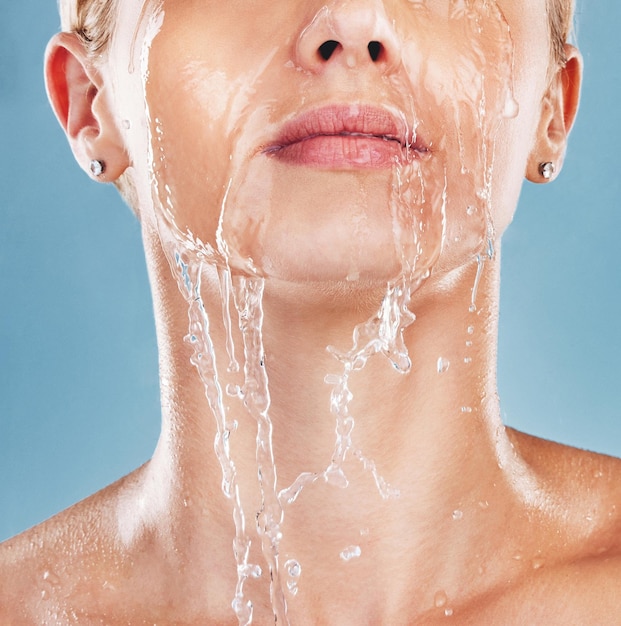 Visage de femme éclaboussures d'eau et nettoyage de la peau bien-être et douche sur fond de maquette de studio bleu Maquette modèle cosmétique et corps de nettoyage avec lavage du visage propre et bain pour l'hygiène et l'hydratation