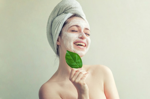 Visage de femme avec feuille verte et crème ou masque nourrissant