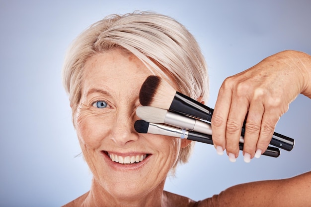 Visage de femme et maquillage avec pinceau cosmétique pour produit de bien-être de beauté ou de soins de la peau en studio Spa soins de santé de luxe pour la peau et modèle senior dermatologie de soins du visage ou d'auto-soins sur fond gris