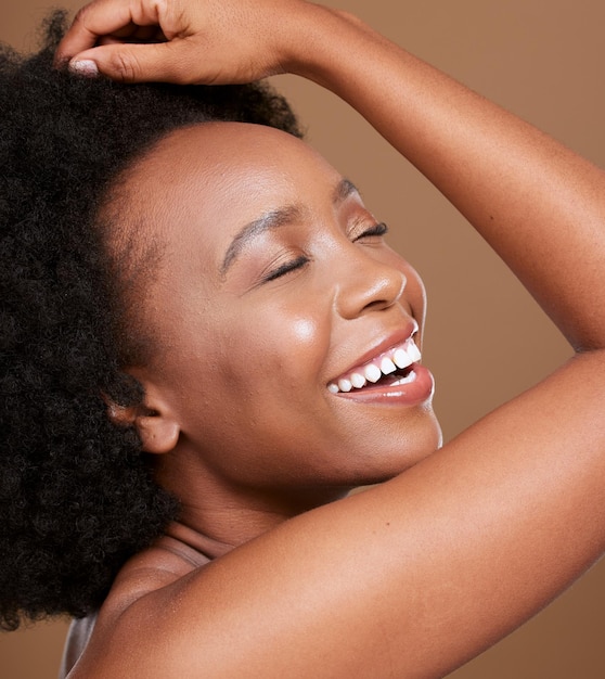 Visage de femme noire et sourire pour les cosmétiques de soins de la peau maquillage de traitement de luxe sur fond de studio marron Une femme afro-américaine se détend en souriant de satisfaction pour les soins du visage et une peau parfaite