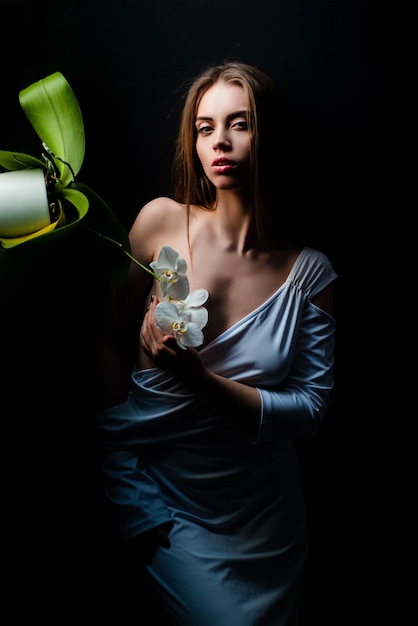 Visage de femme séduisante jeune femme sensuelle posant avec une fleur d'orchidée et un corps sexy beau mode sexy