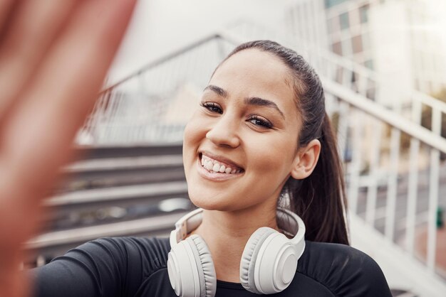 Visage de femme et selfie avec casque et fitness dans la ville heureuse au Brésil sourire en portrait et exercice en plein air Runner cardio et bonheur en photo santé et bien-être avec un mode de vie actif