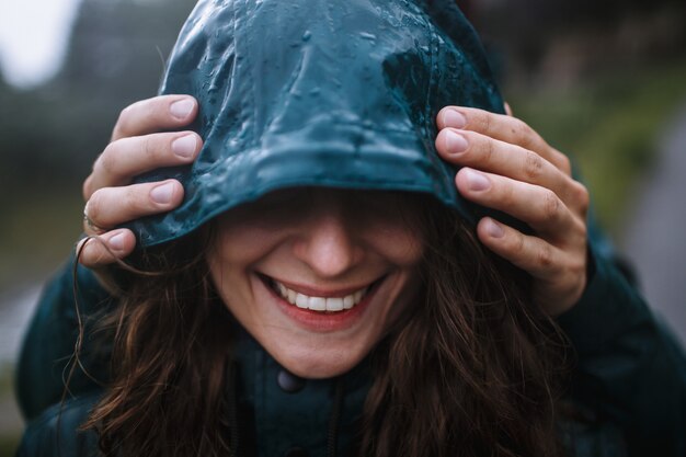 Le visage d'une femme souriante dans un imperméable vert, qui est étreint par derrière par son petit ami