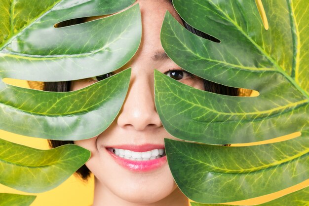 Visage de femme sous des feuilles vertes