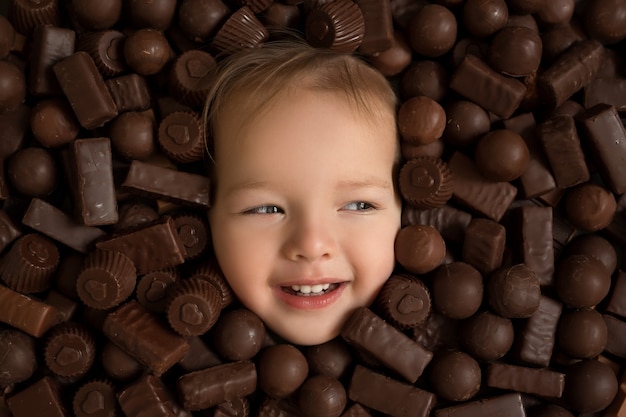 Visage de fille sur fond de chocolats. Une consommation excessive de bonbons est nocive pour la santé