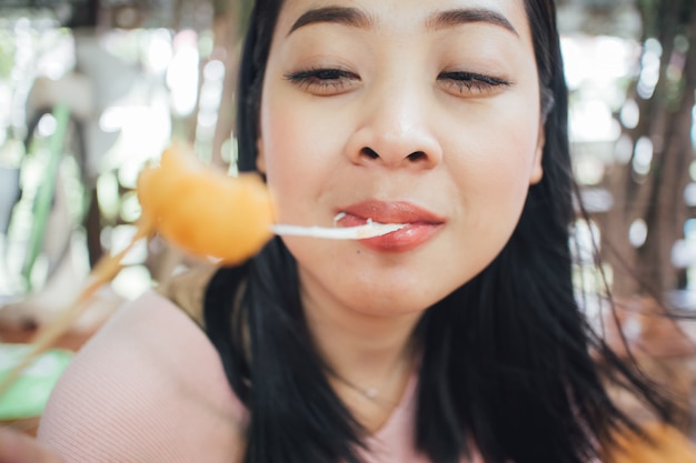 Visage gros plan de femme manger des boules de fromage avec des bâtons.