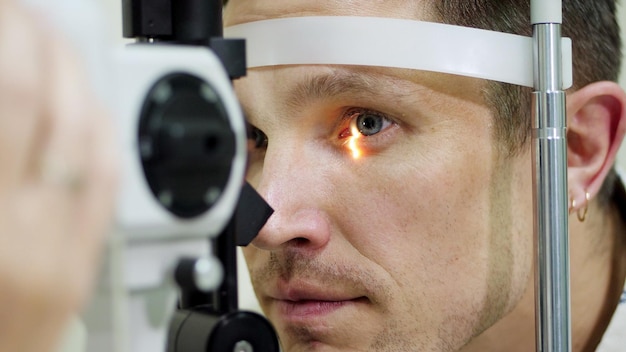 Photo visage en gros plan homme faisant un test oculaire avec un tonomètre sans contact vérifiant la vision