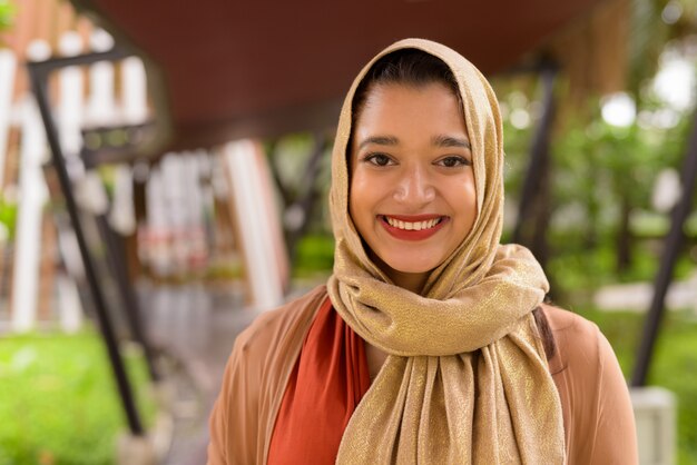Visage d'heureuse jeune belle femme musulmane indienne souriante dans la ville avec la nature