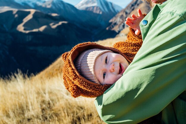 visage heureux d'un bébé dans ses bras dans les montagnes