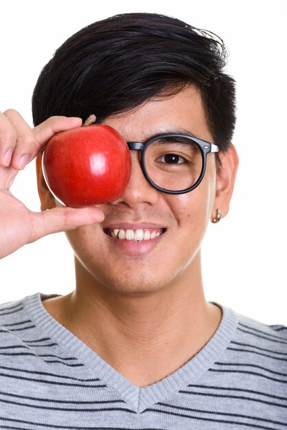 Visage d'heureux homme asiatique souriant tout en couvrant les yeux avec appl rouge