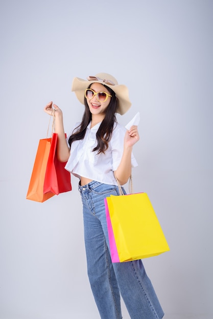 Visage heureux et sourire de jeune femme asiatique tenant une couleur de sac à provisions et projet de loi sur fond blanc.