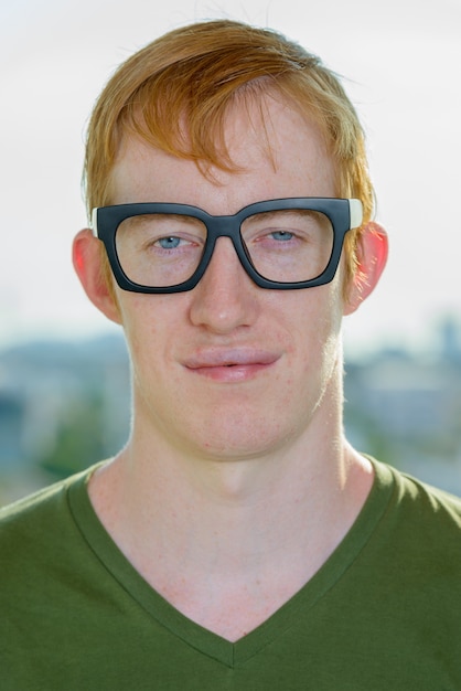 Visage d'homme nerd aux cheveux rouges portant des lunettes contre vue sur la ville
