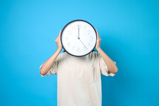 Visage de l'horloge Des gens tenant une horloge sur sa tête isolés sur un fond bleu