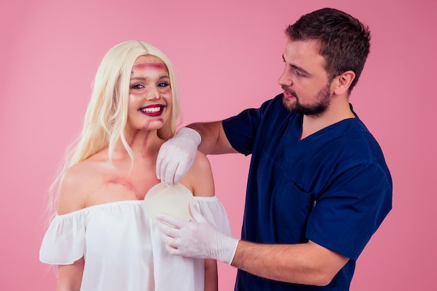 Visage impeccable d'une jeune belle patiente blonde aux cheveux longs et d'une chirurgie de médecin consultant sur l'augmentation mammaire mammoplastiechoisissez une nouvelle taille d'amélioration d'implant de gel de buste