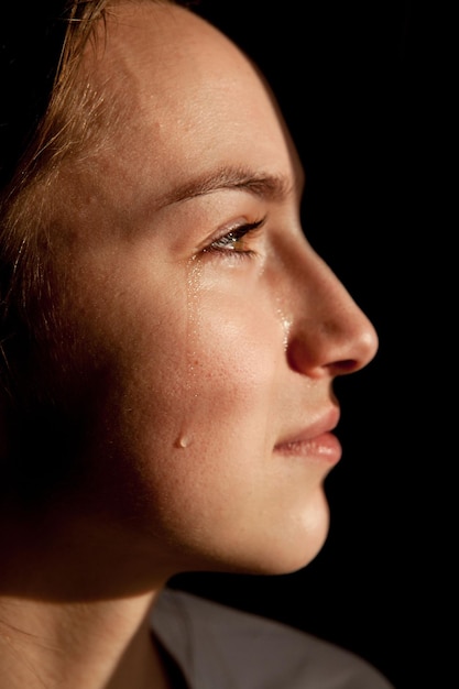 Le visage d'une jeune femme avec une goutte de larme en gros plan