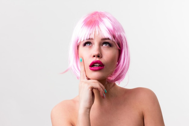 Visage d'une jeune femme avec un maquillage lumineux sur fond rose avec des cheveux froncés en queue de cheval lisse