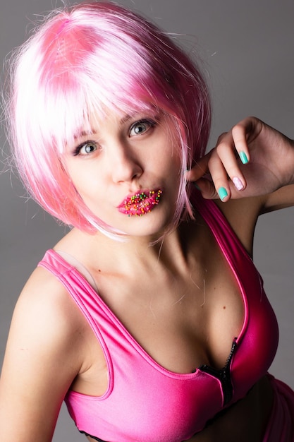 Visage d'une jeune femme avec un maquillage lumineux sur fond rose avec des cheveux froncés en queue de cheval lisse