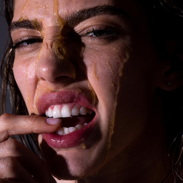 Visage de jeune femme sensuelle avec une goutte de miel en gros plan Modèle sexy avec une goutte de miel sur le visage