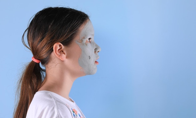 visage de jeune fille avec masque d'argile cosmétique bleu