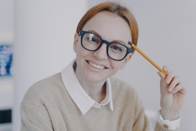 Visage d'une jolie fille réussie Étudiant heureux détendu tenant un crayon et souriant Étude à distance