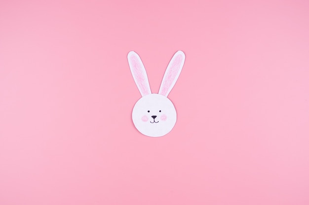 Visage de lapin mignon en papier, sur rose.