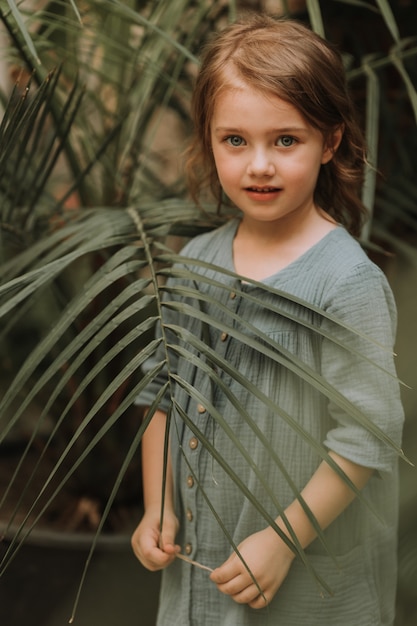 visage d'une petite fille entourée de feuilles tropicales closeup portrait d'un beau bébé