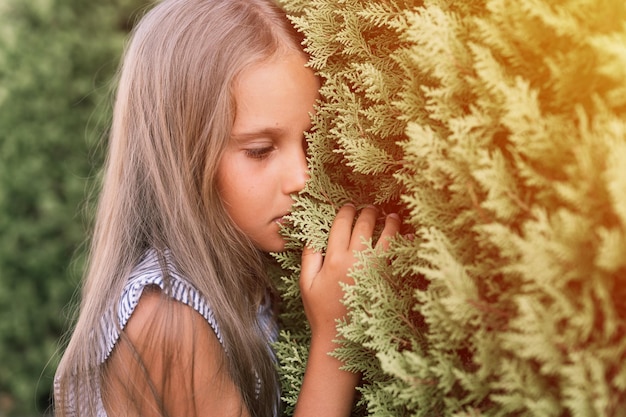 Visage de portrait de candide offensé bouleversé petite fille de huit ans avec de longs cheveux blonds sur fond de plantes vertes pendant un voyage de vacances d'été gen z concept de santé mentale flare