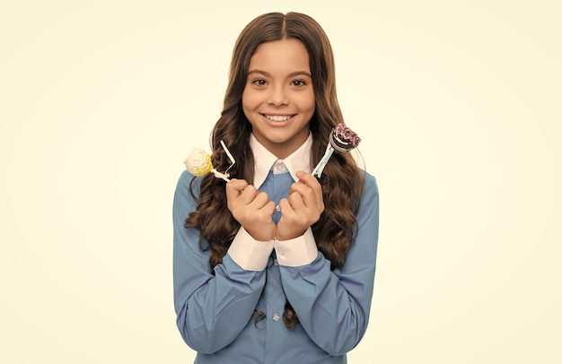 Le visage souriant d'une adolescente aux longs cheveux bouclés tient des bonbons au chocolat sucrés isolés dans un magasin de bonbons blancs.