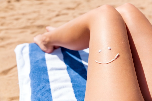 Le visage souriant est dessiné sur une jambe féminine bronzée et lisse sur le fond de la mer.