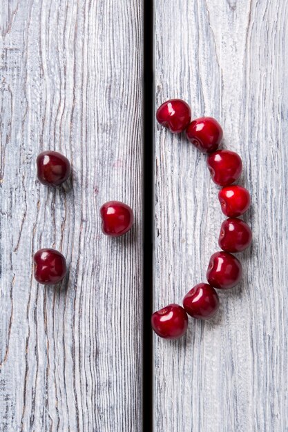 Visage souriant fait de cerises fruits rouges sur fond bois rester en bonne santé et être heureux l'art est plus proche ...