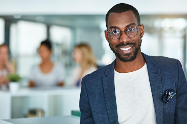 Visage souriant intelligent d'un homme d'affaires professionnel ou employé d'entreprise dans un bureau occupé Un portrait heureux et intelligent d'un homme d'affaires noir sympathique avec le lieu de travail comme arrière-plan et espace de copie