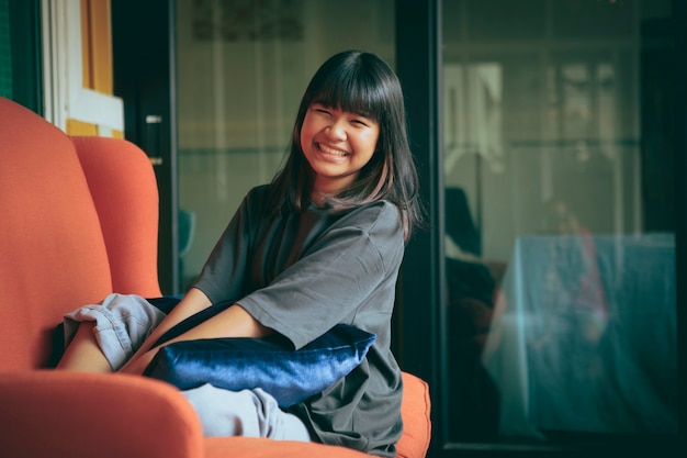 Visage souriant à pleines dents d'adolescent asiatique, détendant dans le salon à la maison