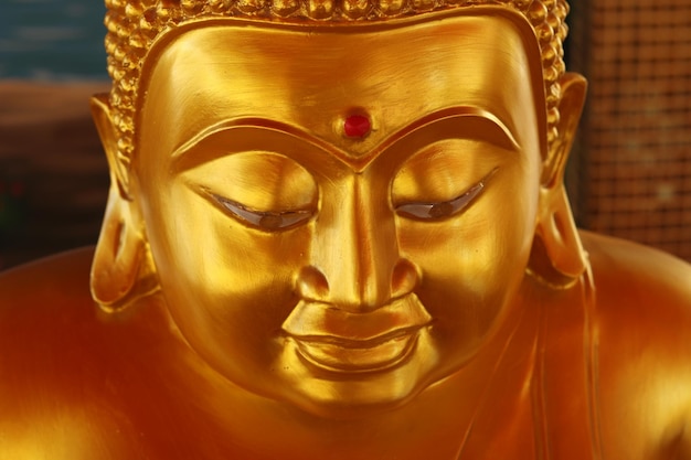 Le visage de la statue de Bouddha de couleur dorée avec un fond flou