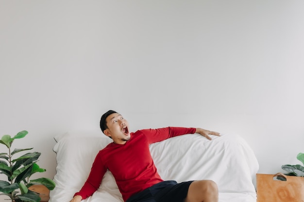 Visage surpris d'un homme asiatique dans la maison avec un espace de copie publicitaire sur le mur