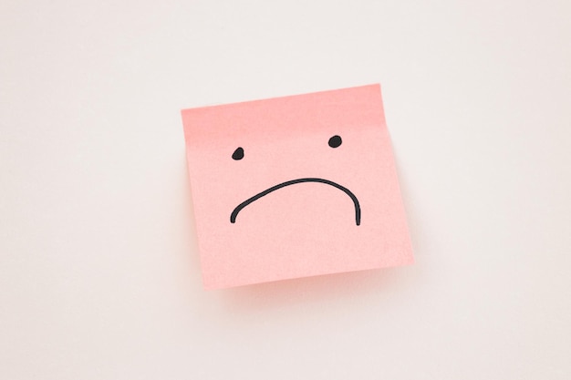 Visage triste sur post-it sur fond blanc