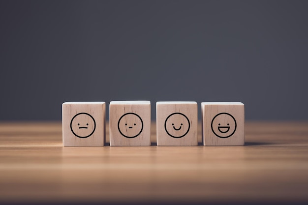 Visage triste à sourire sur des cubes de blocs de bois disposés sur une table en bois Idée de beaucoup penser à faire face et sourire enfin