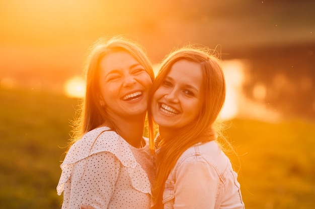 visages heureux et sourires sincères de deux meilleurs amis sur le fond du lac du soir