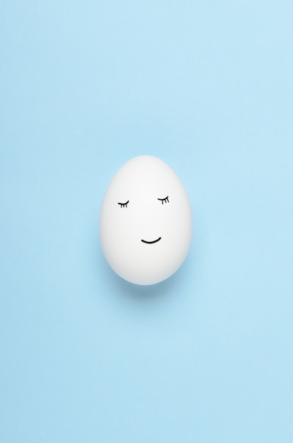 Visages Kawaii sur des oeufs blancs sur fond bleu. Dessins animés, nourriture de décoration pour enfants. Vue de dessus, pose à plat.