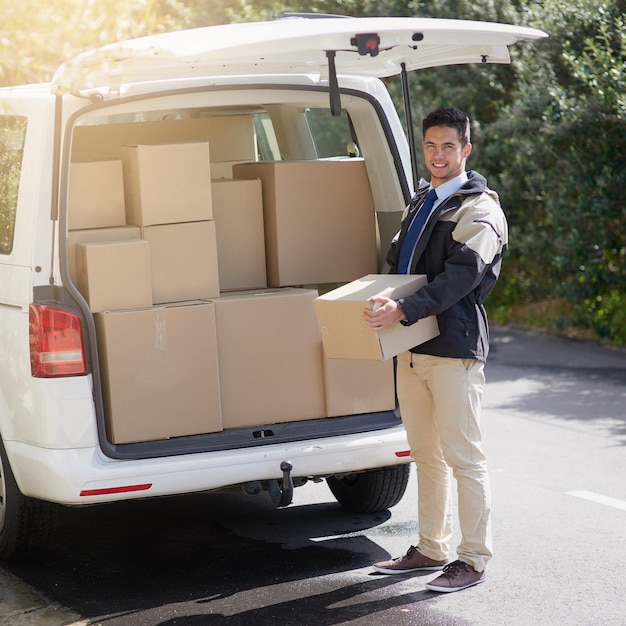 Viser l'excellence du service Portrait d'un sympathique livreur déchargeant des cartons de sa camionnette